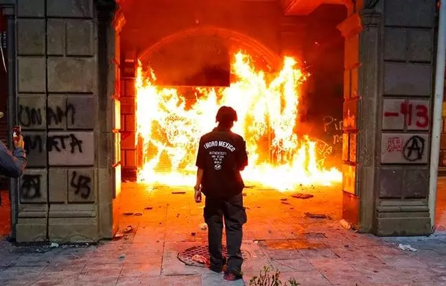 Enfrenta grupo de encapuchados a policías; queman y roban negocios.